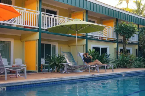 Poolside lounge chairs at Kauai Shores Hotel beside guest room patios and balconies.