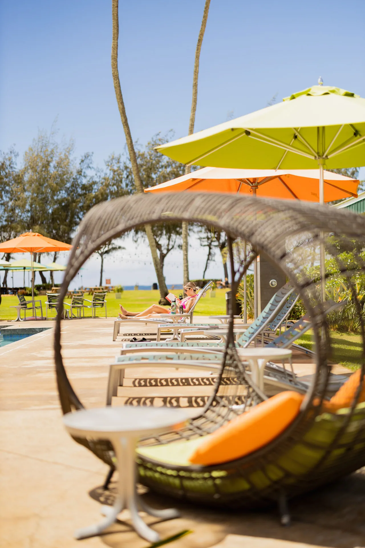 Poolside loungers, umbrellas, and a hanging chair at Kauai Shores Hotel.