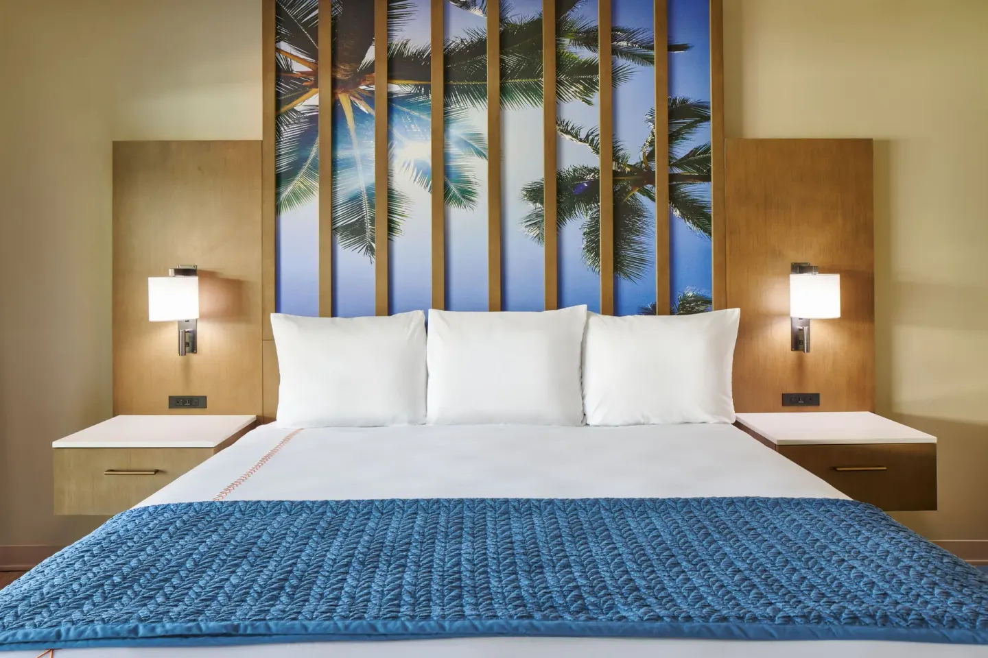 Garden View king bed with palm artwork and bedside lights at Kauai Shores Hotel.