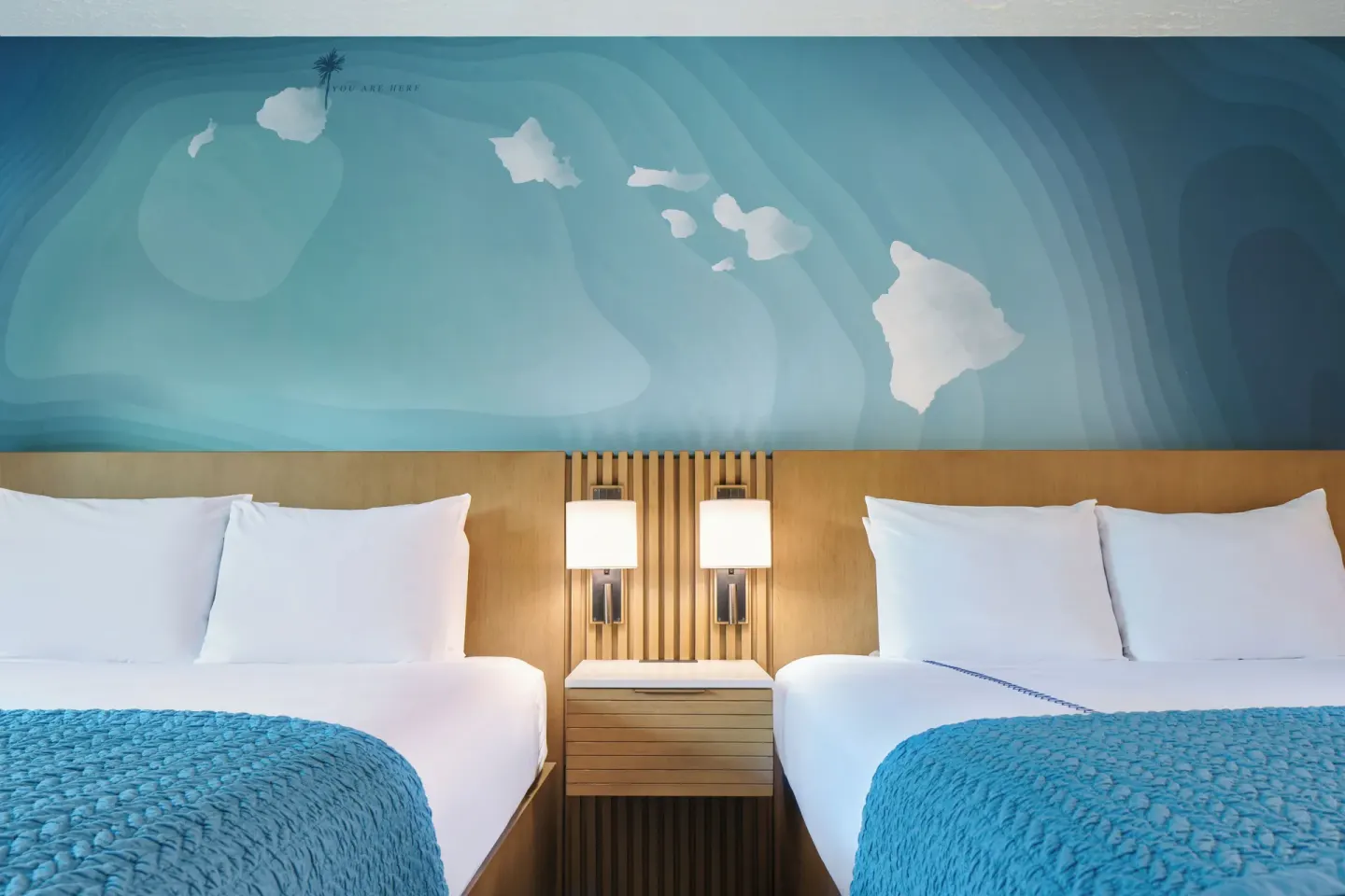 Two beds in an Ocean View room at Kauai Shores Hotel beneath a blue island mural.