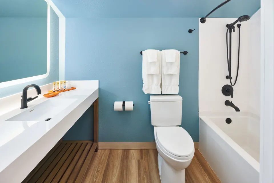 Newly renovated studio bathroom with tub shower and long vanity at Kauai Shores Hotel.