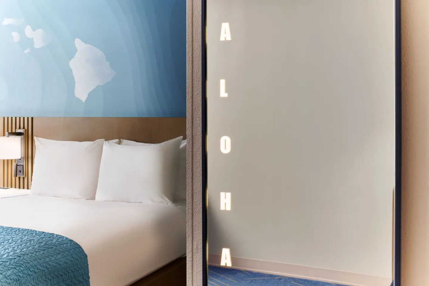 Studio bed and illuminated aloha mirror detail at Kauai Shores Hotel.