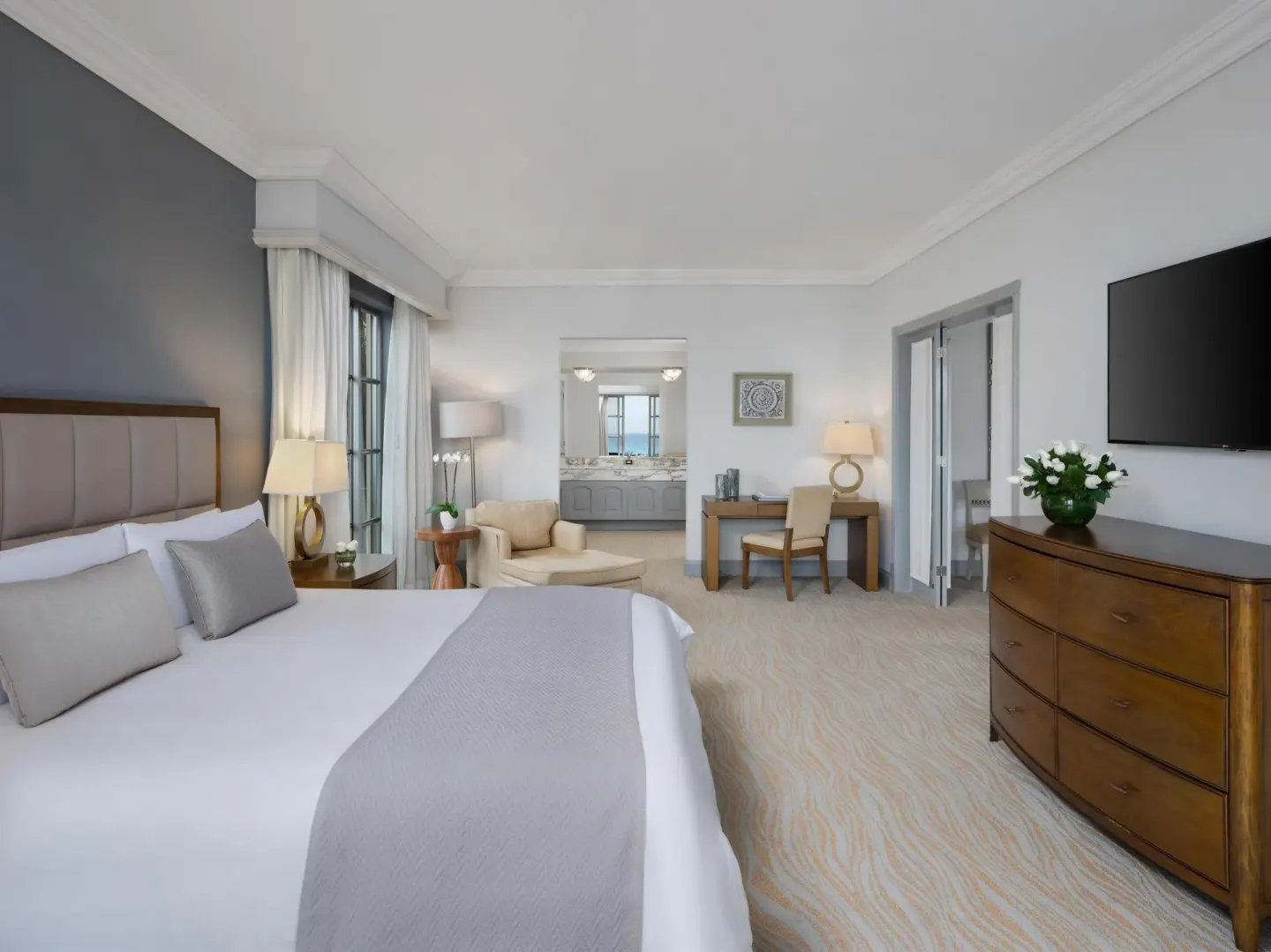 Guest room with king bed, seating, desk, TV, and bathroom view at Kempinski Hotel Cancún.