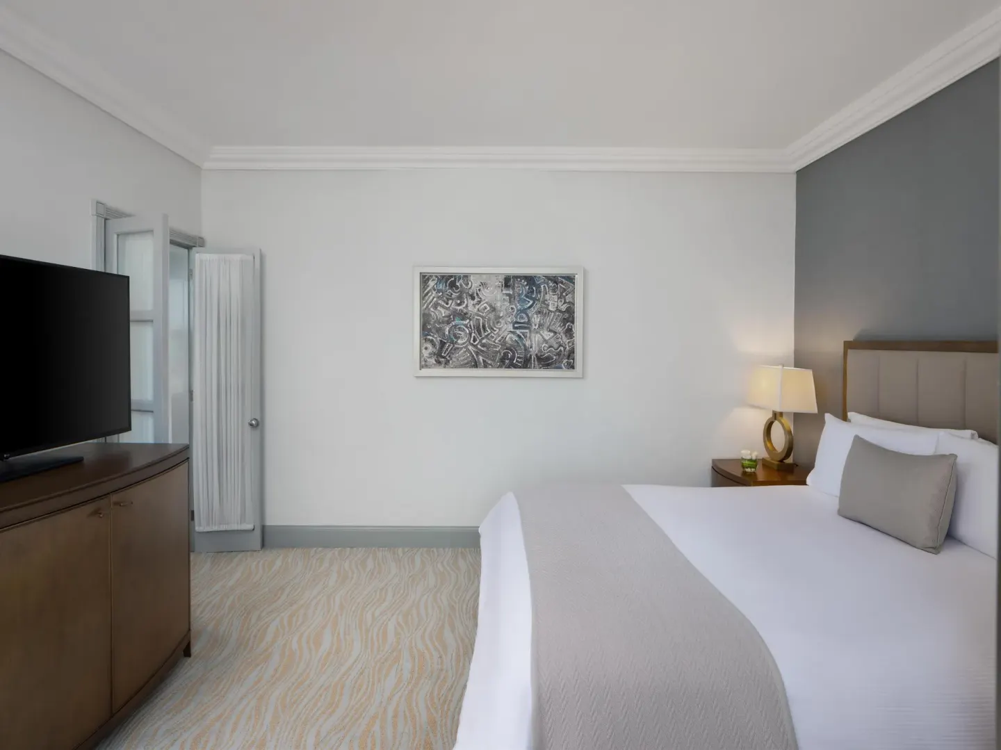 Guest room with a king bed, wall art and television at Kempinski Hotel Cancún.