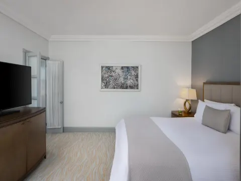 Guest room with a king bed, wall art and television at Kempinski Hotel Cancún.