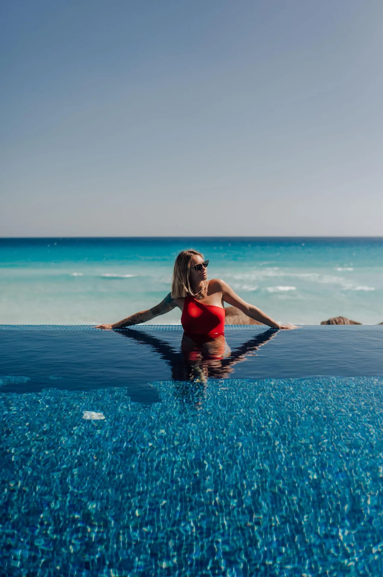 Guest in an infinity-edge pool overlooking the sea at Kempinski Hotel Cancún.