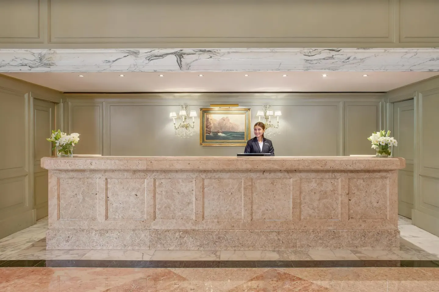 Marble front desk with a staff member in the lobby of Kempinski Hotel Cancún.