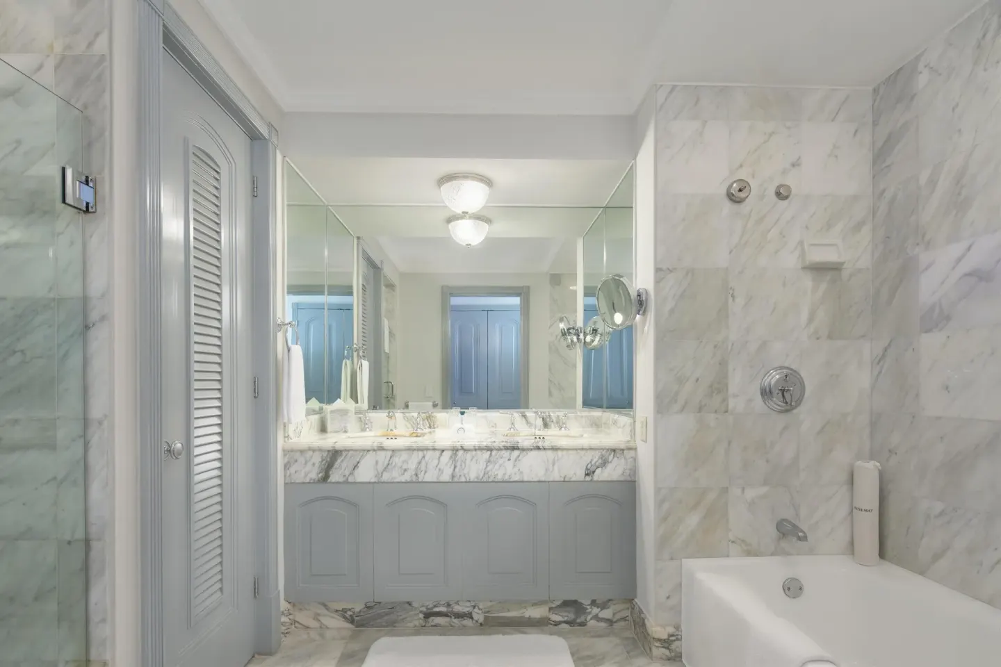Marble guest bathroom with vanity, bathtub, and glass shower at Kempinski Hotel Cancún.