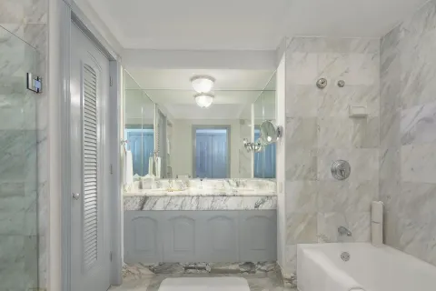 Marble guest bathroom with vanity, bathtub, and glass shower at Kempinski Hotel Cancún.