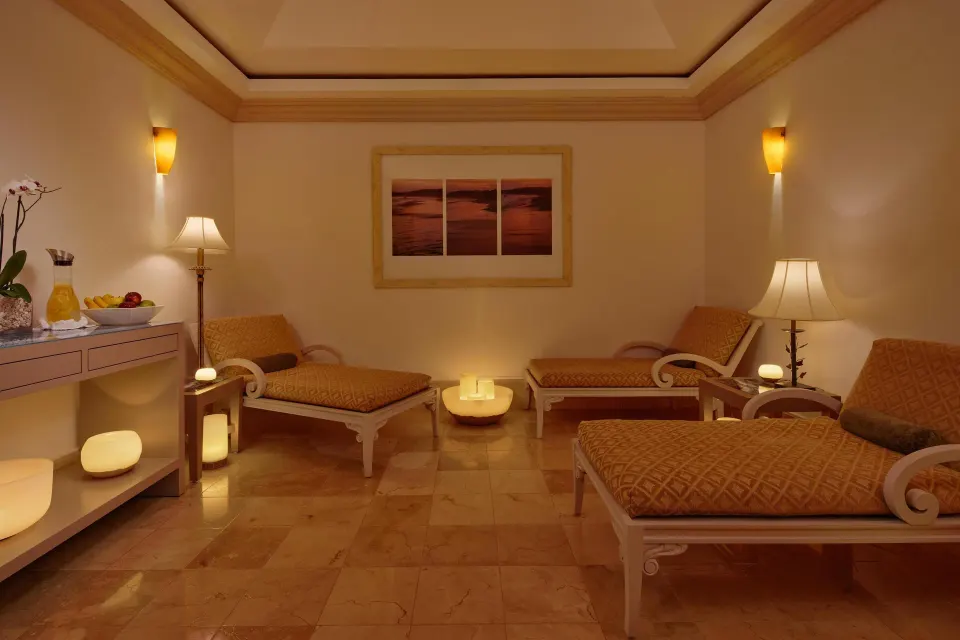 Spa relaxation room with cushioned loungers and candles at Kempinski Hotel Cancún.