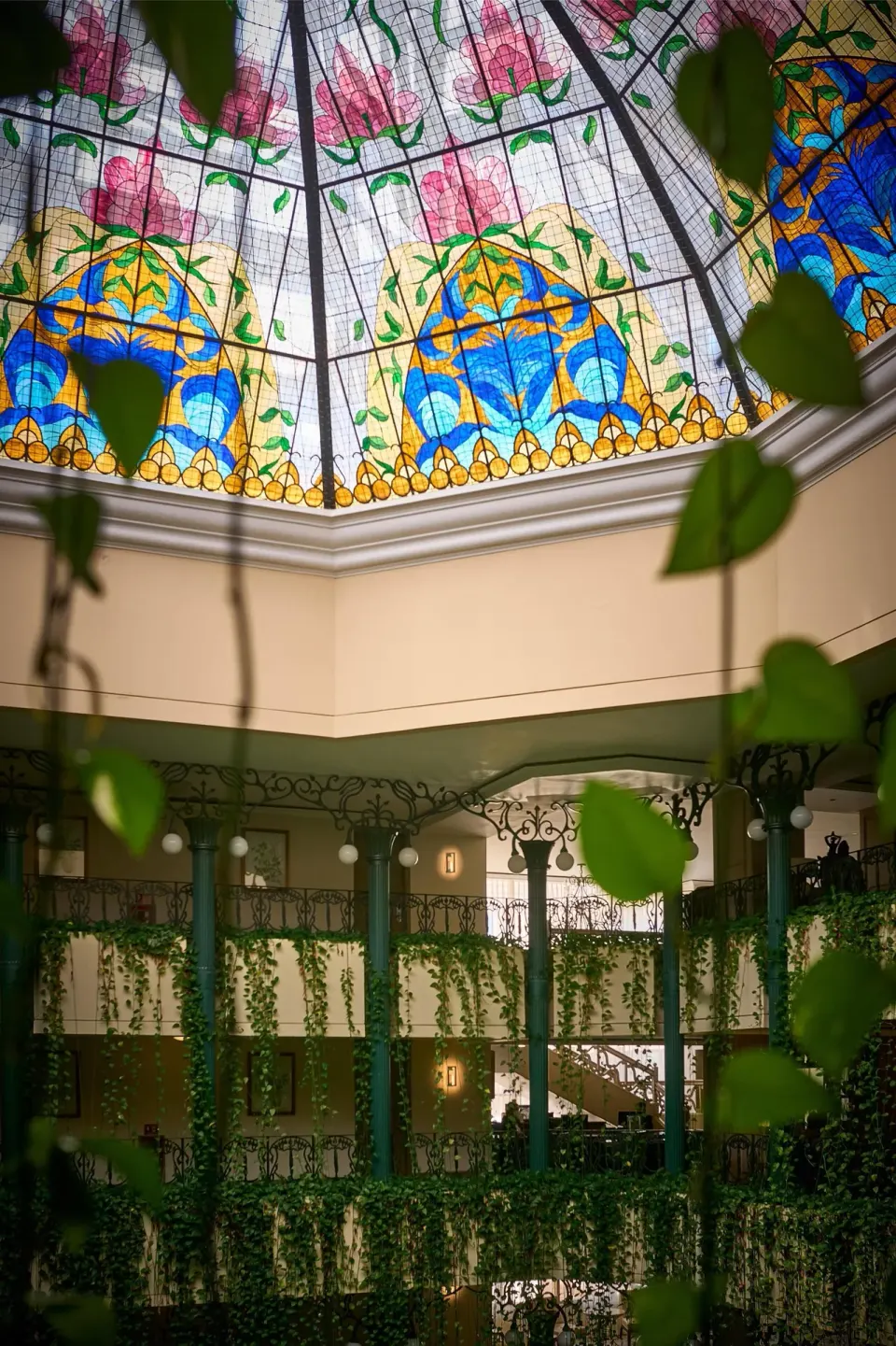 Stained-glass atrium ceiling and hanging greenery at Kempinski Hotel Cancún.