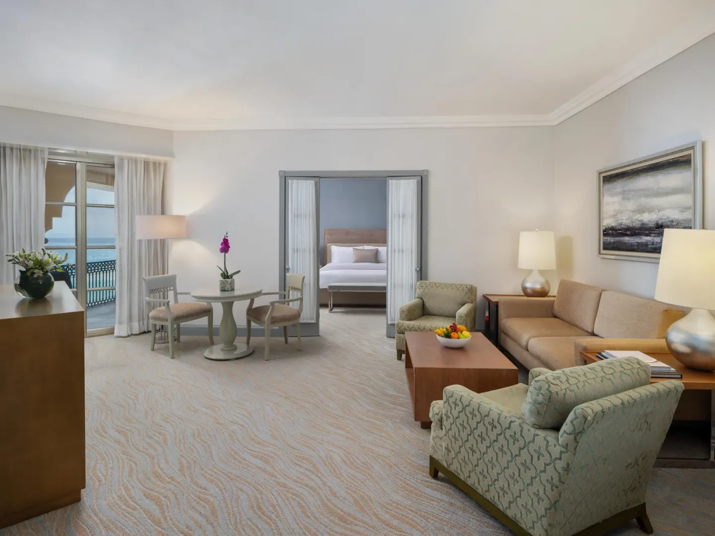 Suite living room with balcony, seating area, and bedroom beyond at Kempinski Hotel Cancún.