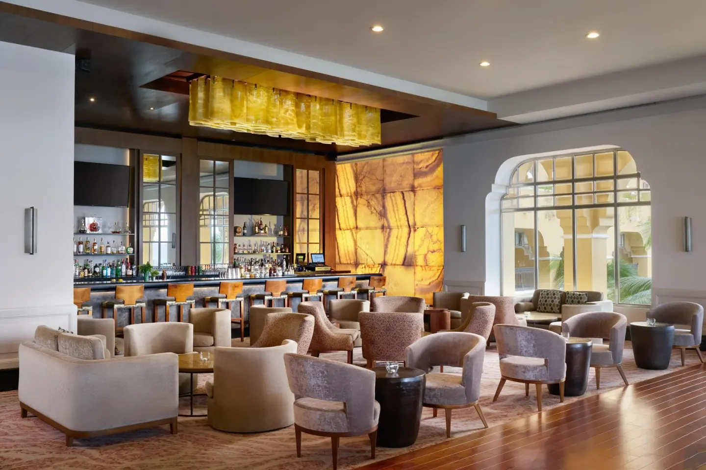 Bar lounge with curved seating and backlit stone wall at Kempinski Hotel Cancún.