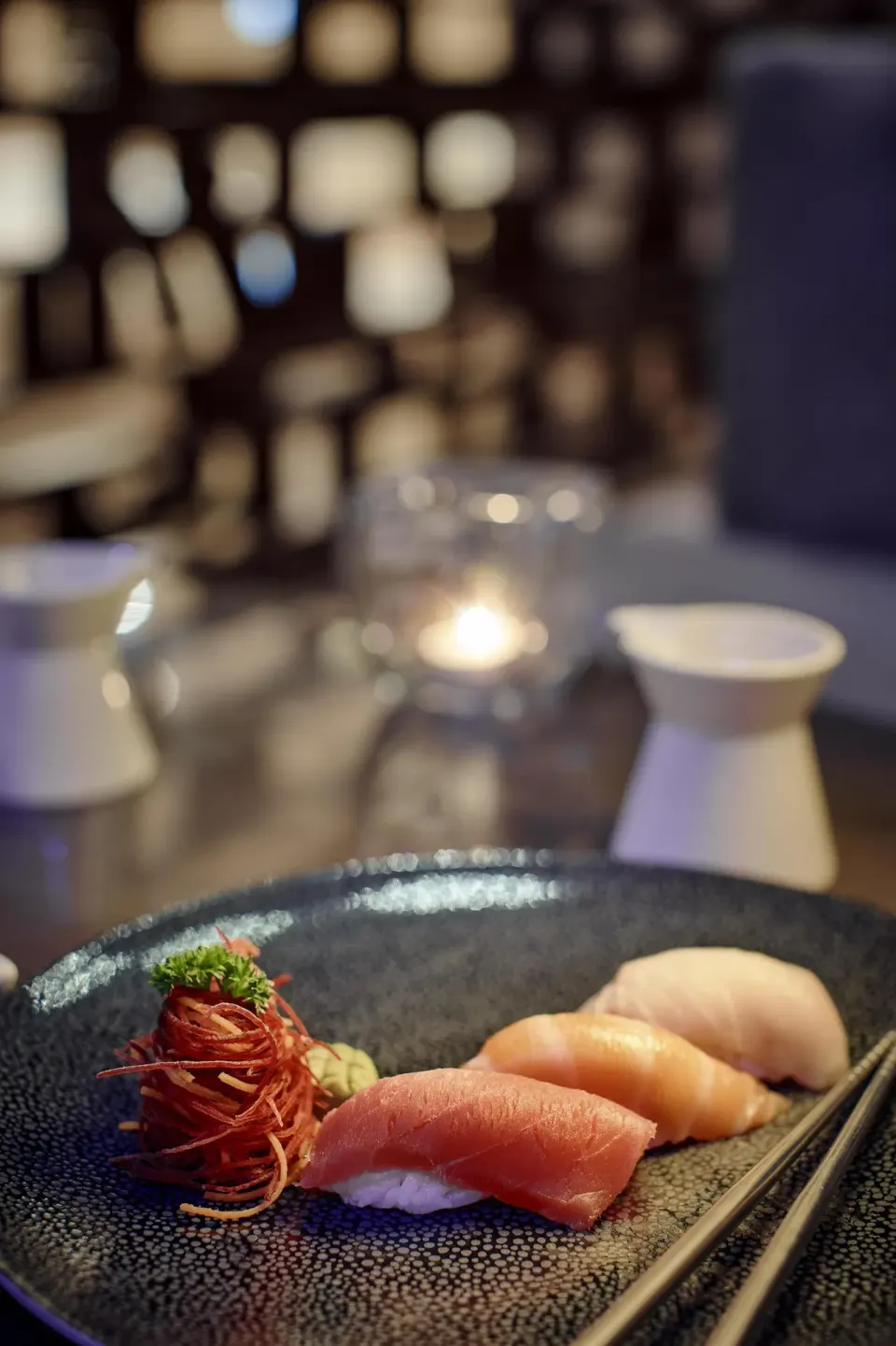 Sushi plate with nigiri and garnish in a dim lounge at Kempinski Hotel Cancún.
