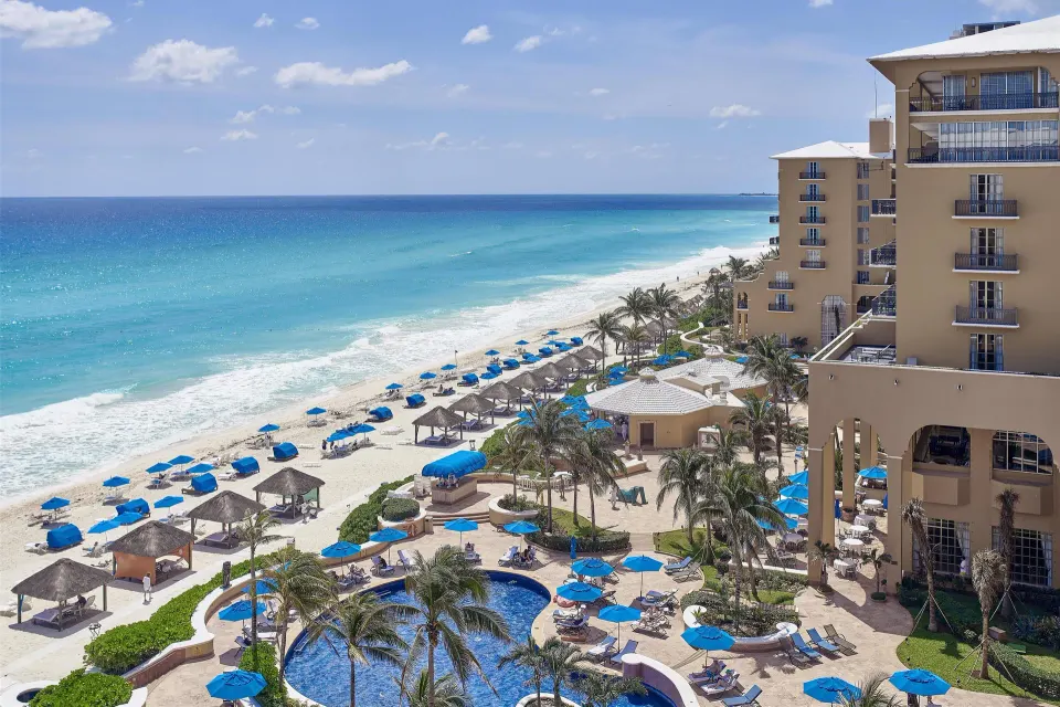 Seaside view of beach, pools, and hotel towers at Kempinski Hotel Cancún.