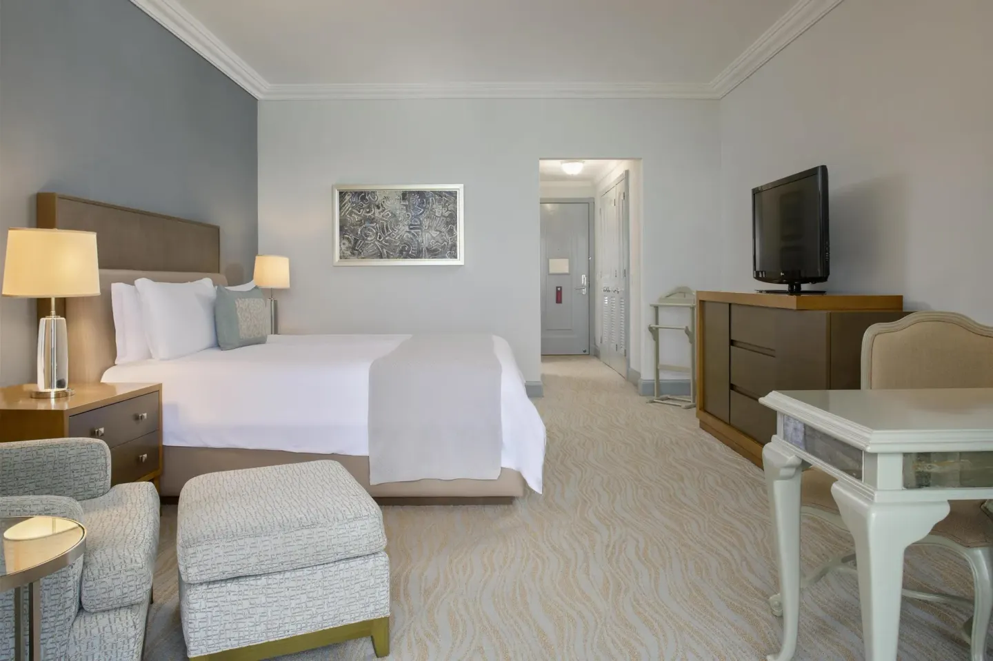 Deluxe seaside room with king bed, armchair, and desk at Kempinski Hotel Cancún.