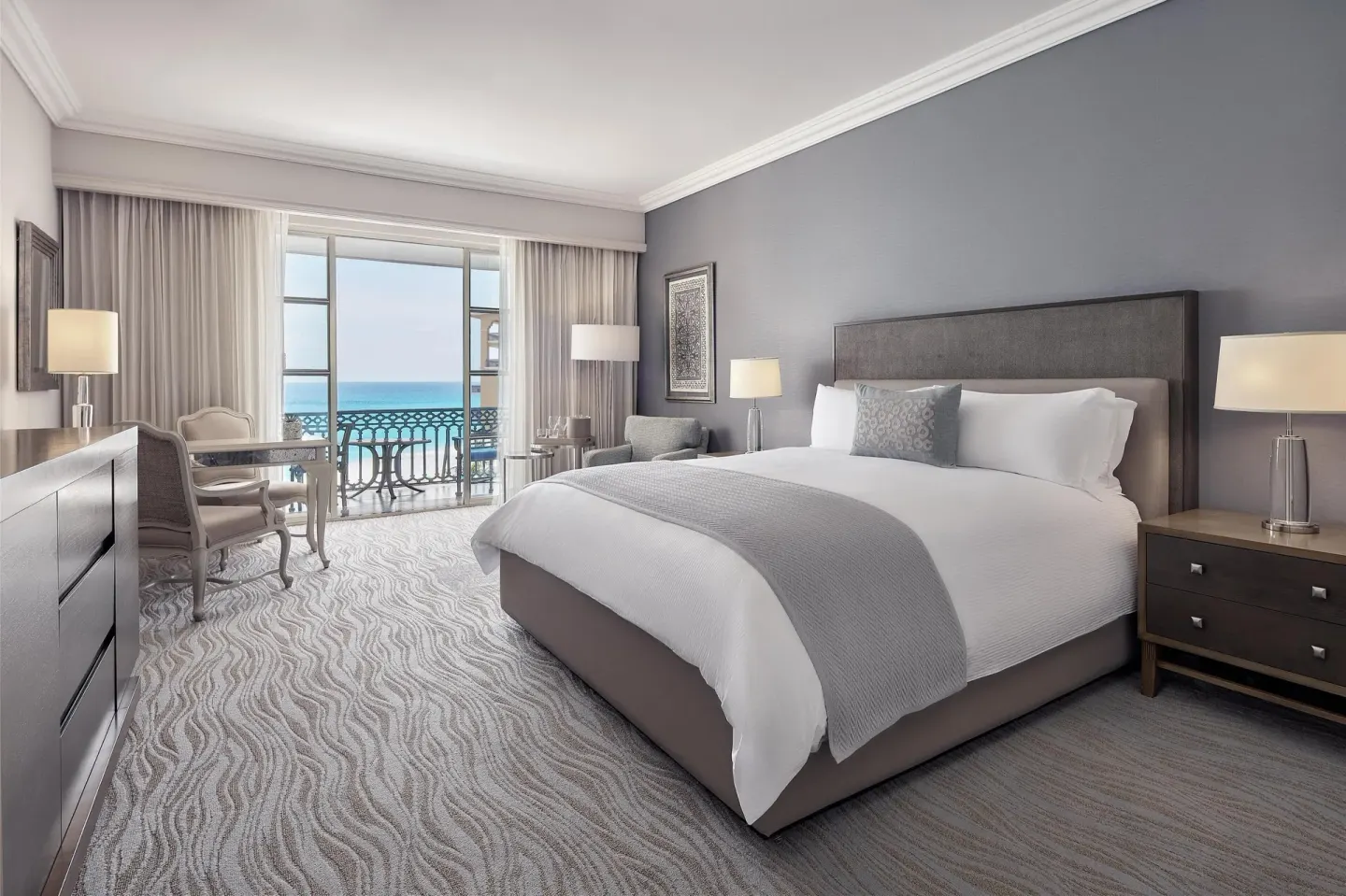 Deluxe seaside room with king bed, armchair, and balcony at Kempinski Hotel Cancún.