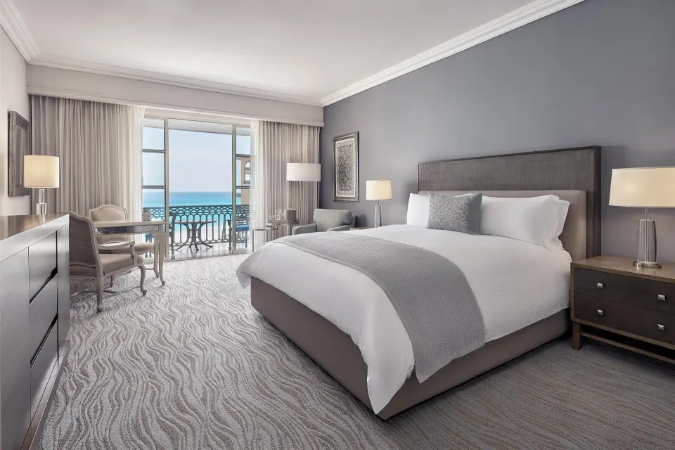 Deluxe seaside room with king bed, armchair, and balcony at Kempinski Hotel Cancún.