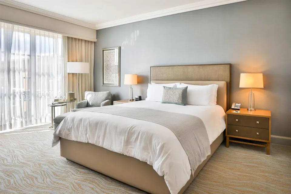 Deluxe seaside room king bed with bedside lamps at Kempinski Hotel Cancún.