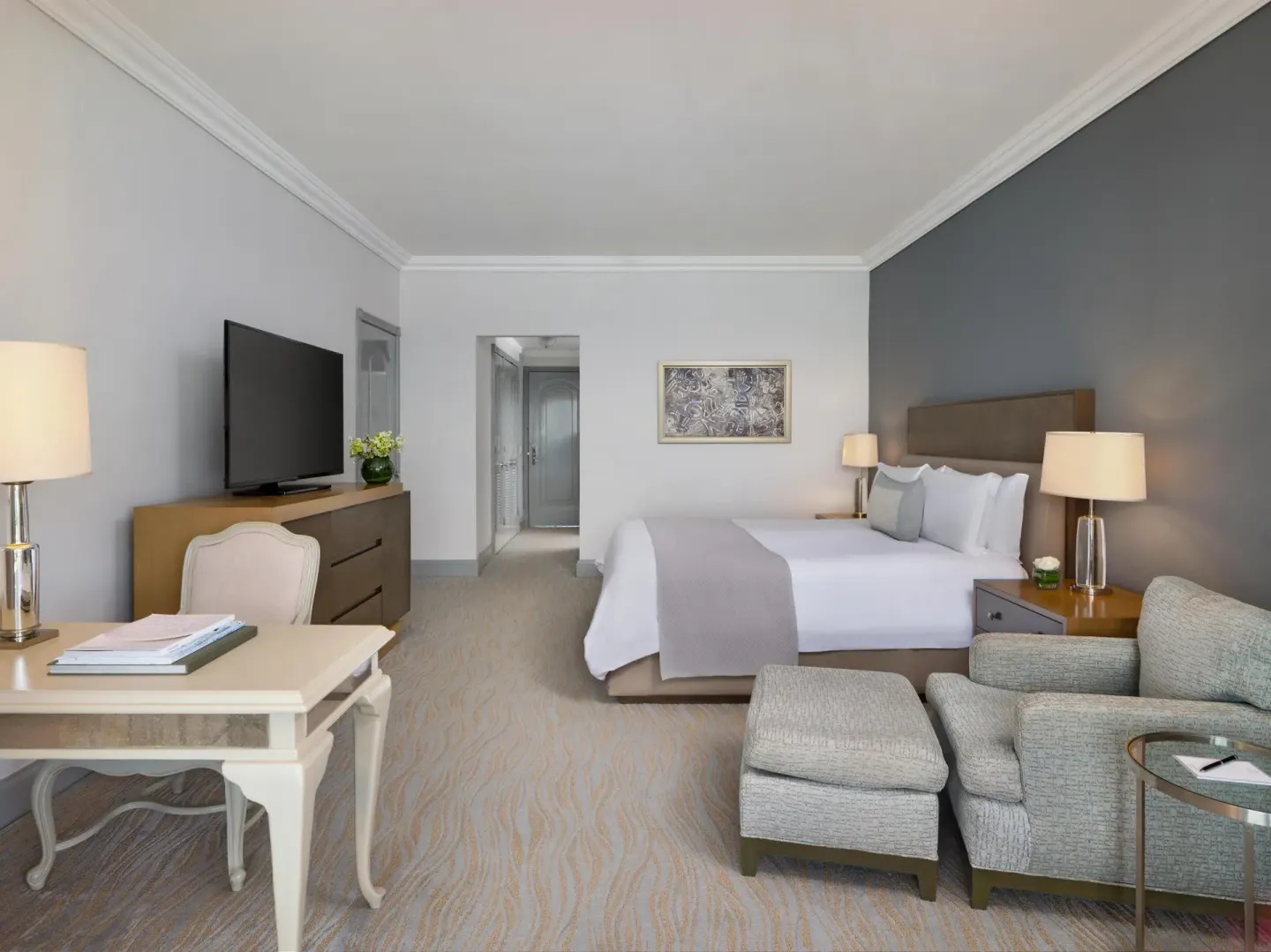 Deluxe seaside room with king bed, sofa chair, desk, and TV at Kempinski Hotel Cancún.