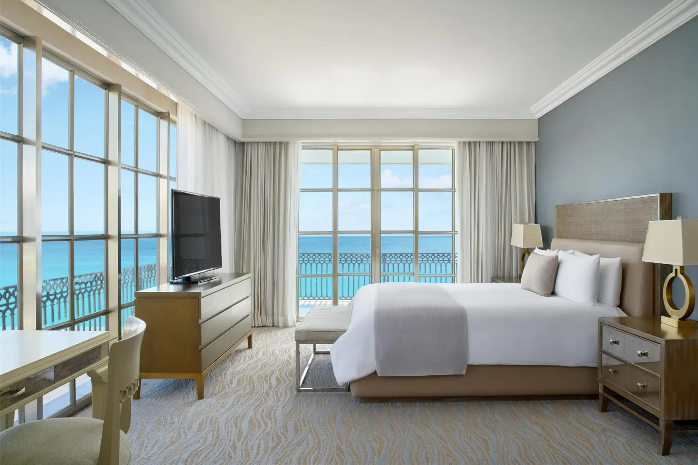 Panoramic Suite bedroom with king bed, desk and sea-facing windows at Kempinski Hotel Cancún.