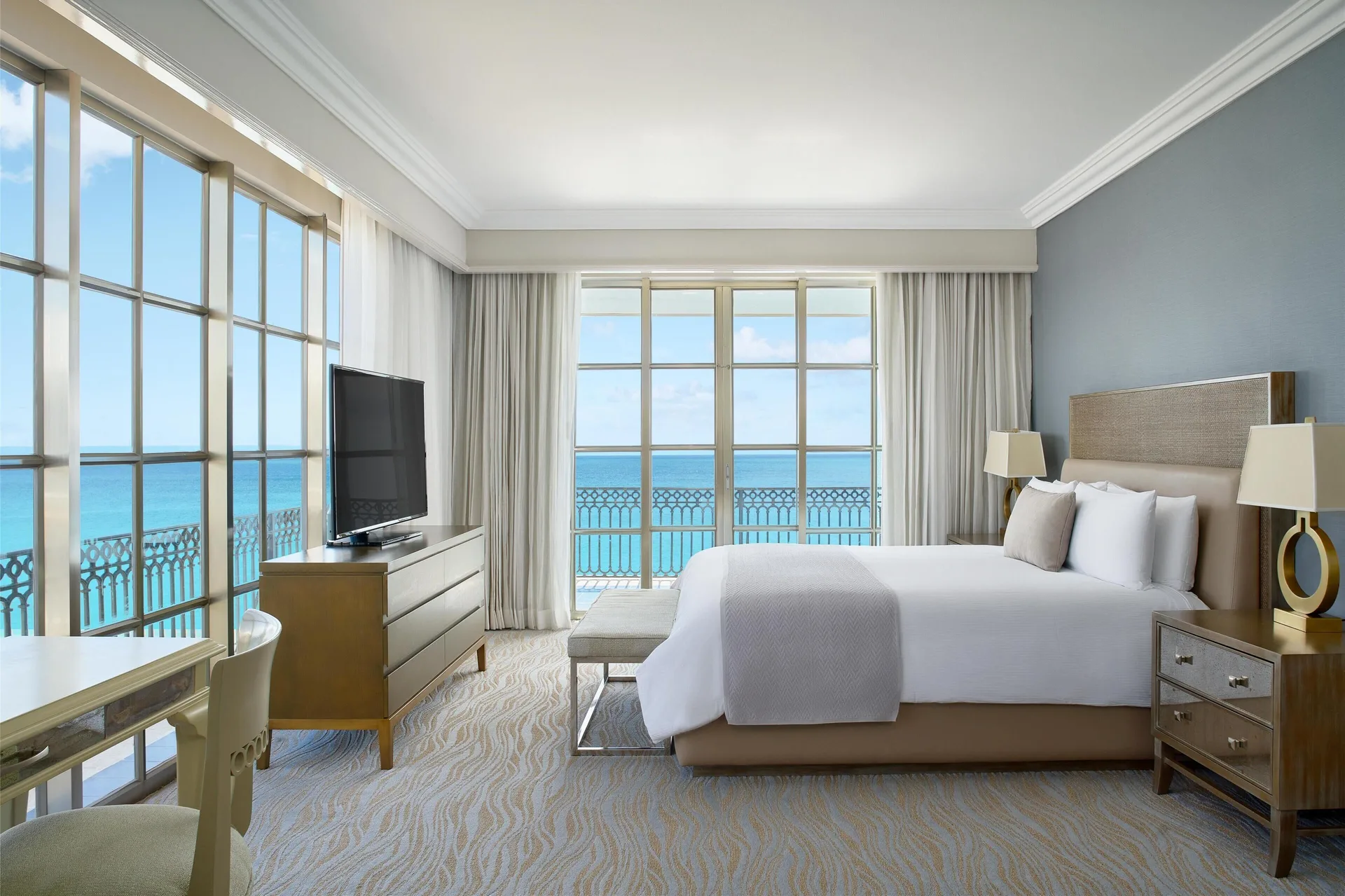 Panoramic Suite bedroom with king bed, desk and sea-facing windows at Kempinski Hotel Cancún.
