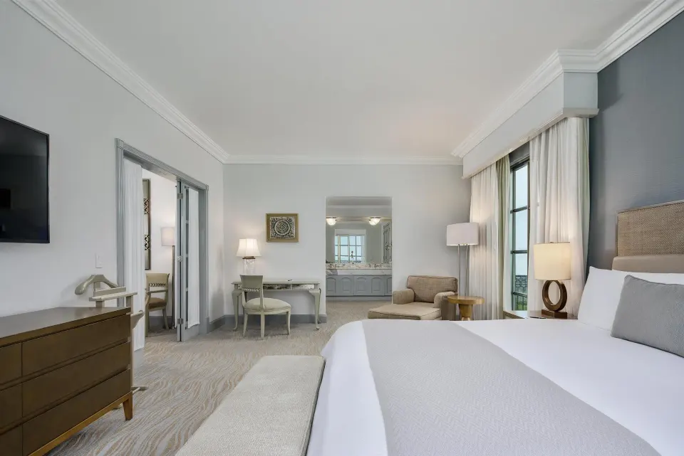 Panoramic Suite bedroom with king bed, seating area and vanity view at Kempinski Hotel Cancún.