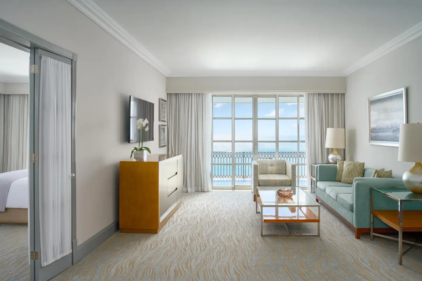 Panoramic Suite living room with sofa and ocean-facing windows at Kempinski Hotel Cancún.