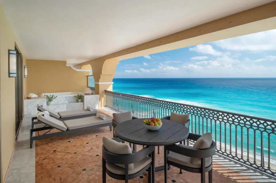 Presidential Suite balcony with loungers, round table and turquoise ocean at Kempinski Hotel Cancún.