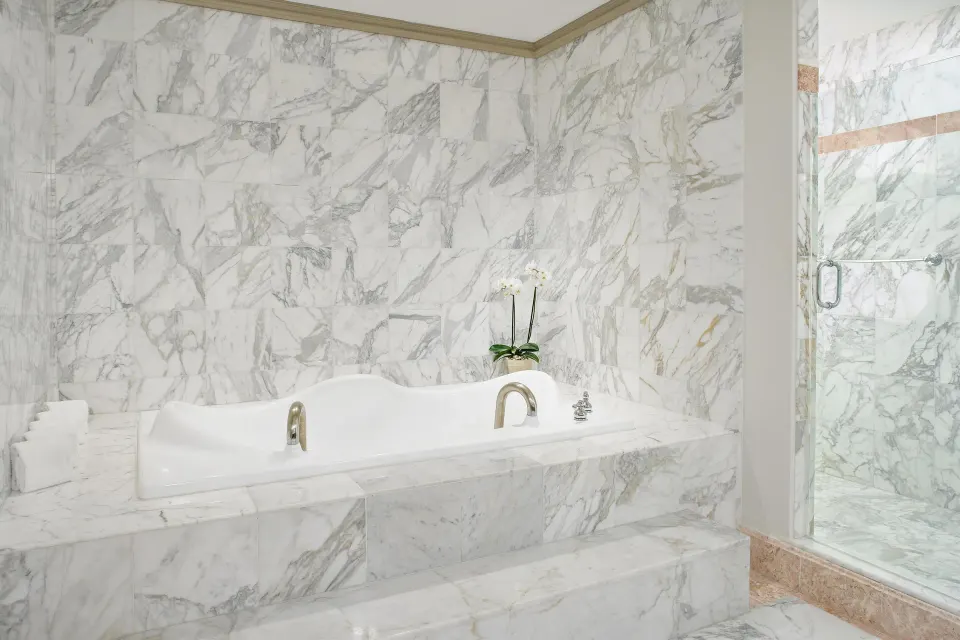 Marble bathroom with soaking tub and glass shower in the Presidential Suite at Kempinski Hotel Cancún.