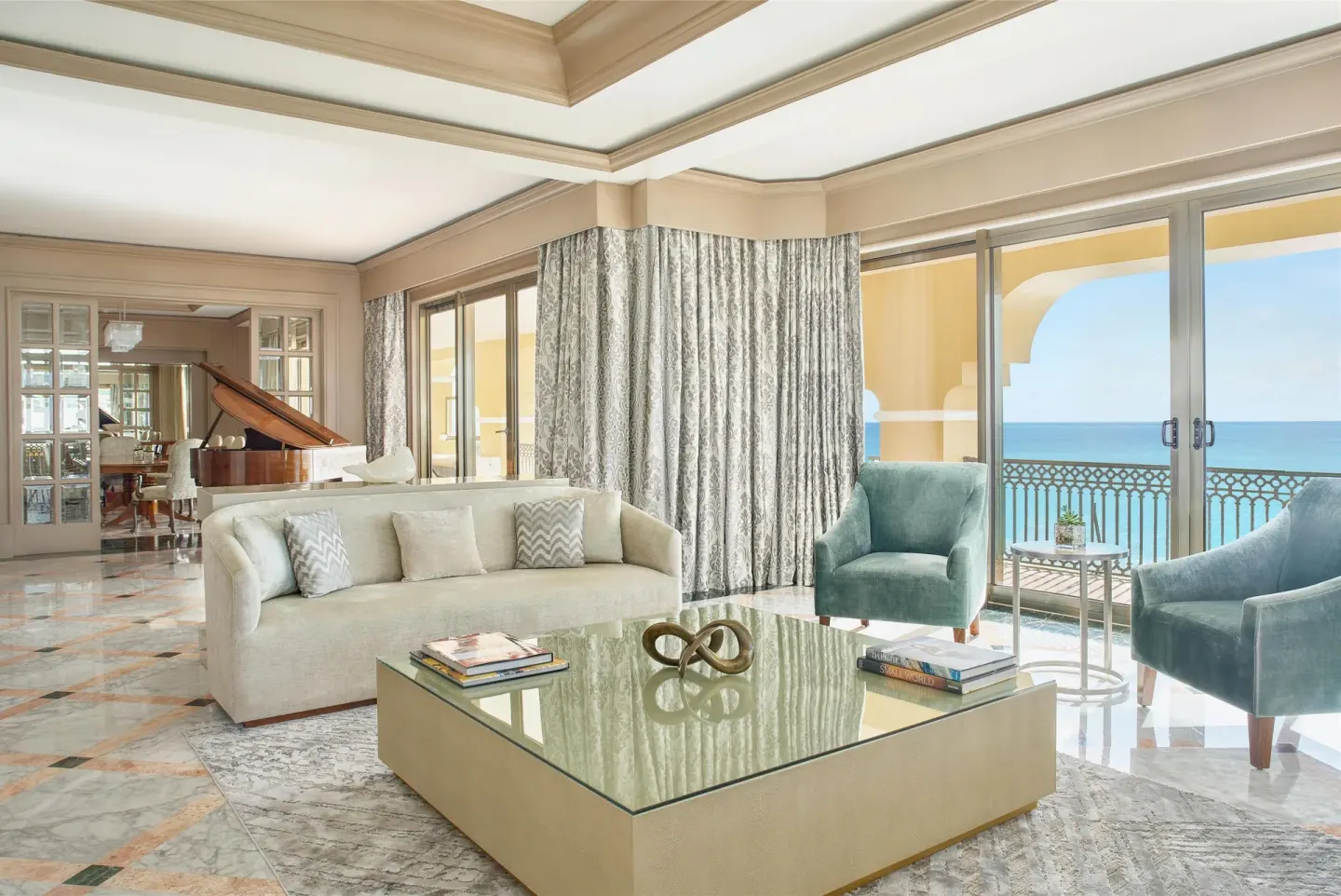Presidential Suite living room with sofa, armchairs and ocean-facing doors at Kempinski Hotel Cancún.