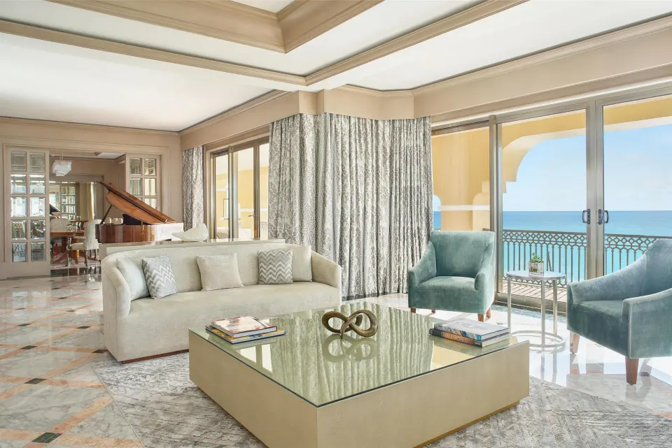 Presidential Suite living room with sofa, armchairs and ocean-facing doors at Kempinski Hotel Cancún.