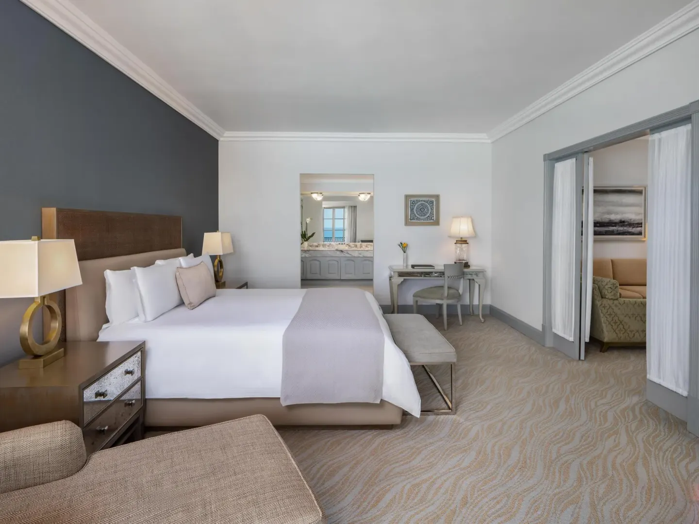 Seaside suite king bedroom with desk and open sitting room at Kempinski Hotel Cancún.