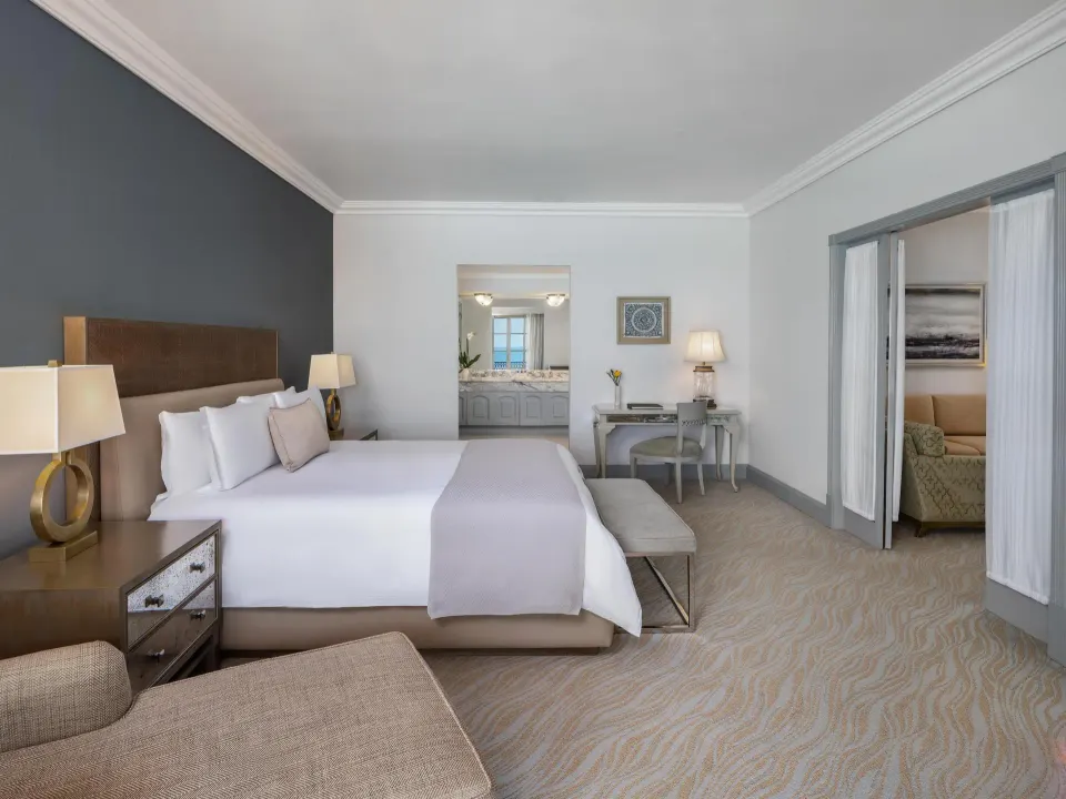 Seaside suite king bedroom with desk and open sitting room at Kempinski Hotel Cancún.