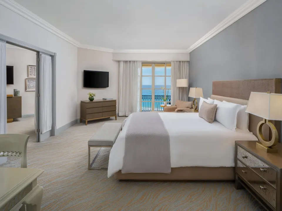Seaside suite king bedroom with TV, dresser and balcony view at Kempinski Hotel Cancún.