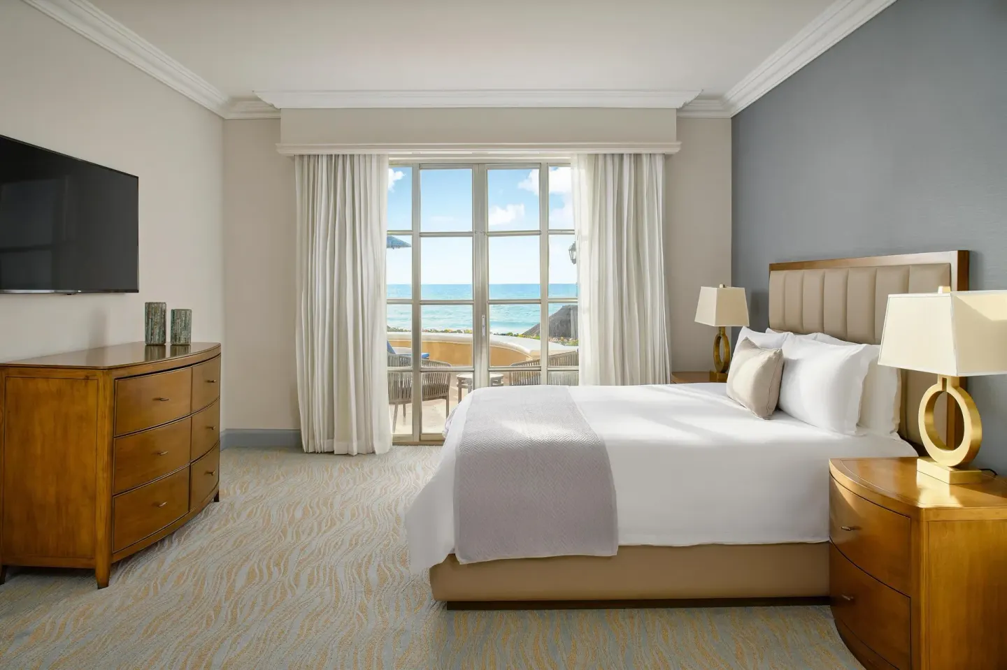 Saasil Suite king bedroom with dresser, TV, and ocean-facing windows at Kempinski Hotel Cancún.