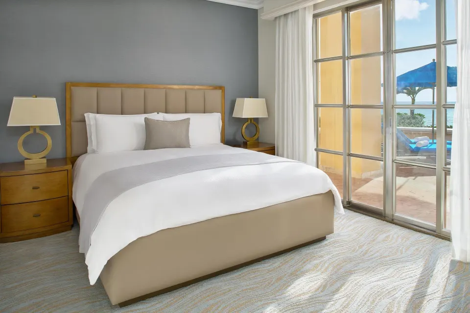 Saasil Suite king bed beside glass doors to the terrace at Kempinski Hotel Cancún.