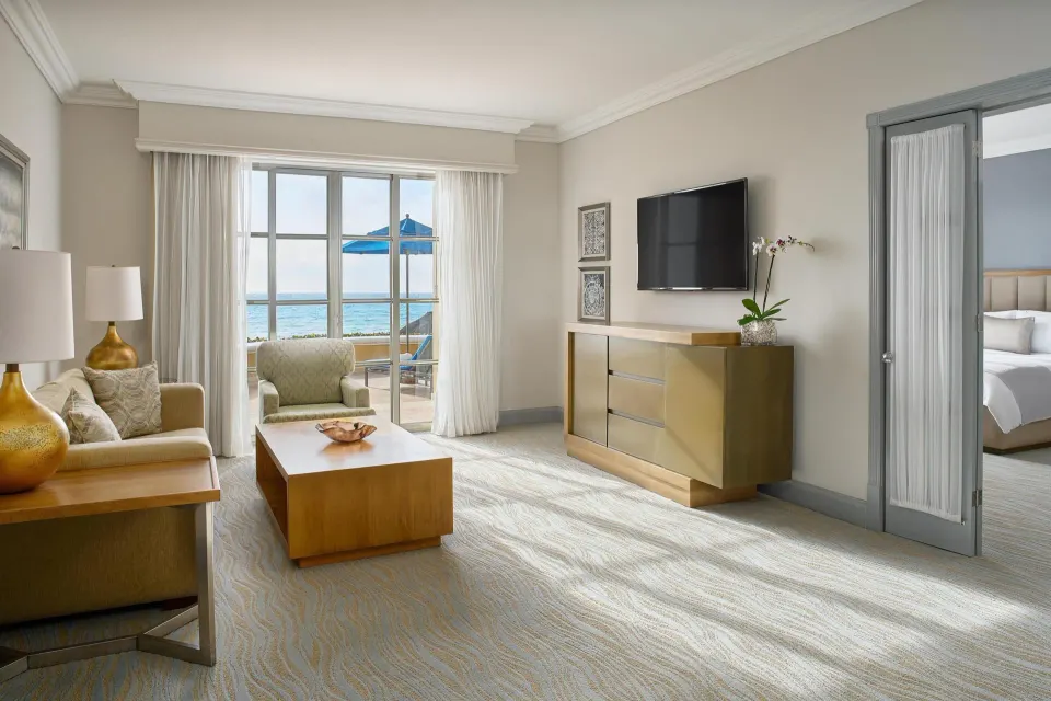 Saasil Suite living room with sofa, TV, and terrace view at Kempinski Hotel Cancún.