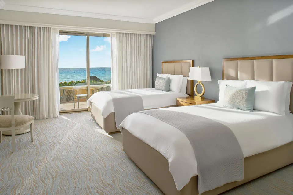 Saasil Suite bedroom with two double beds and a sea-facing balcony at Kempinski Hotel Cancún.