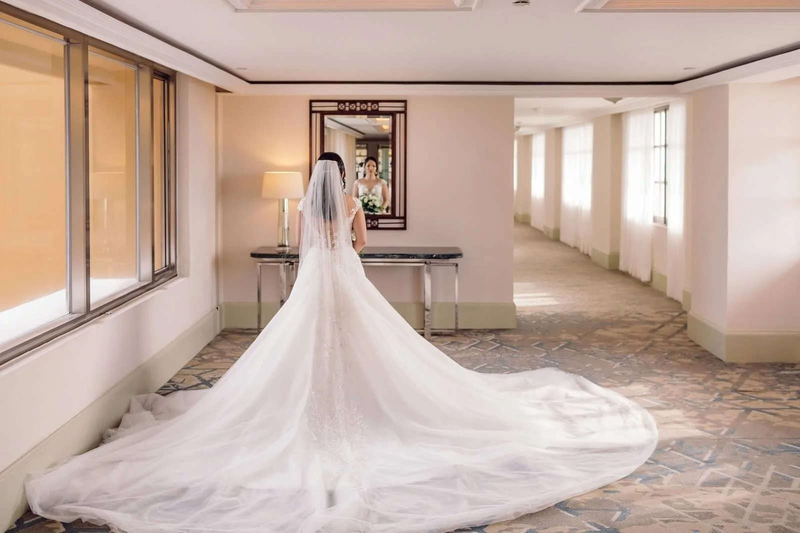 Bride in a long veil standing in an indoor corridor at Kempinski Hotel Cancún.