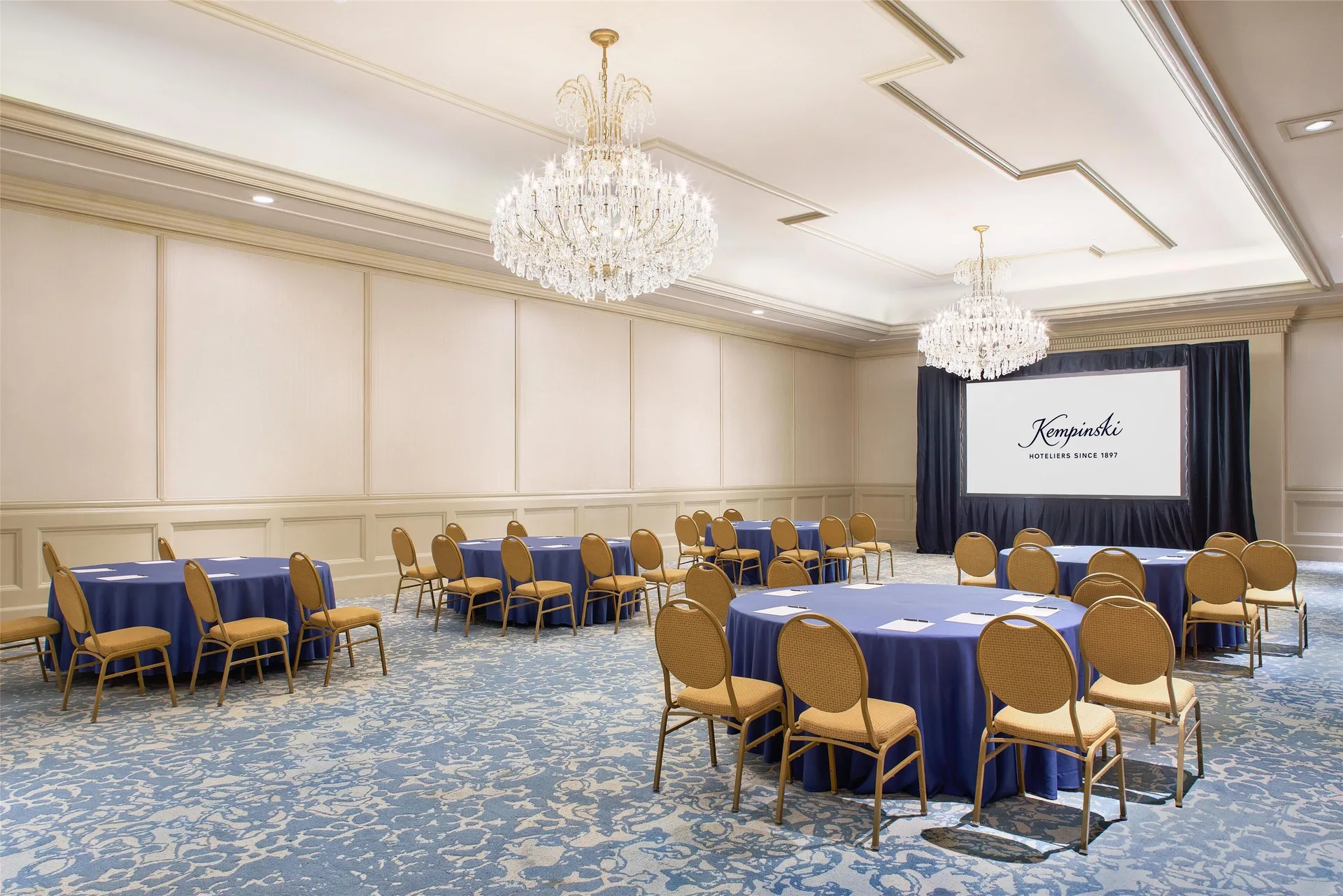 Meeting room with round tables and screen at Kempinski Hotel Cancún.