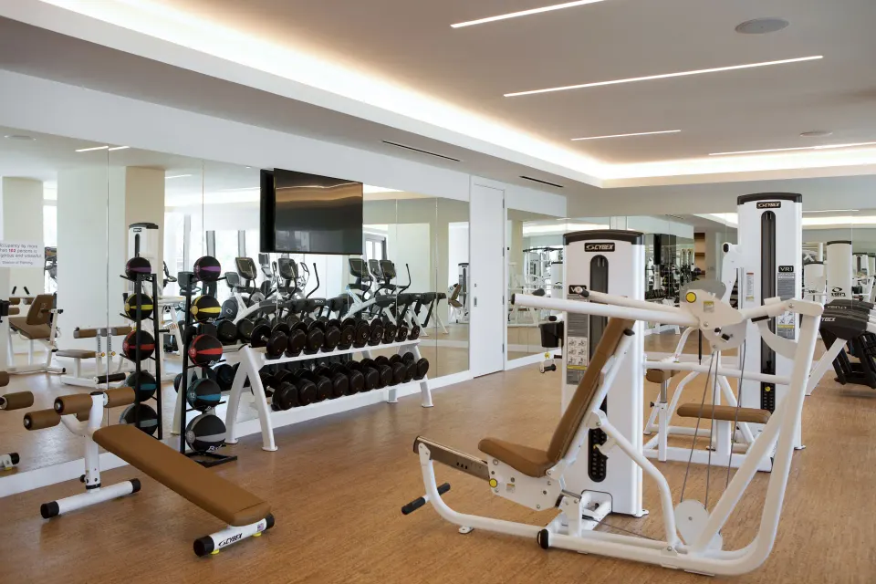 Gym interior with weight rack, benches and mirrored wall at Kimpton Seafire Resort + Spa