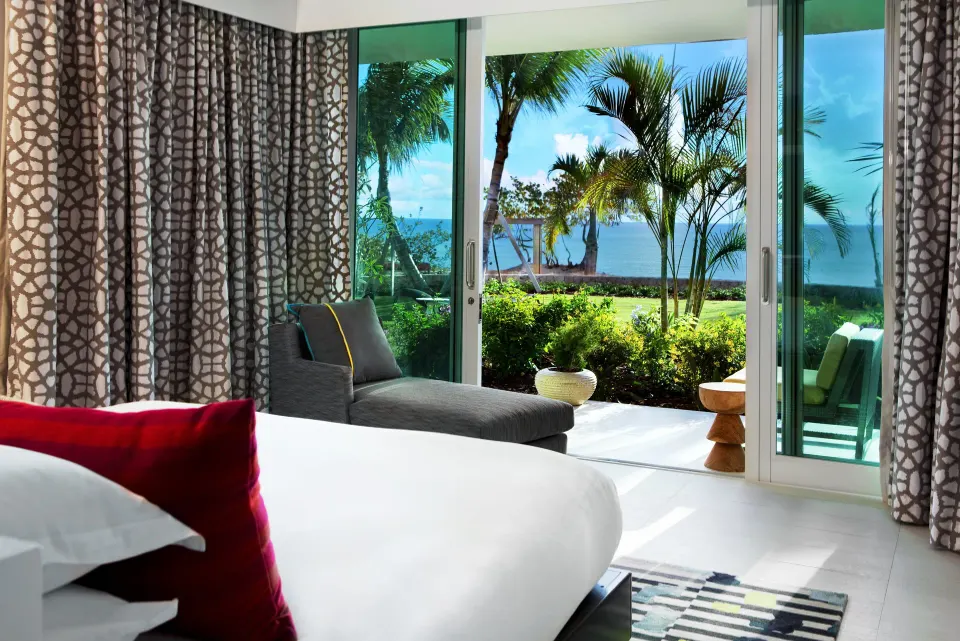 King bed opening to lush gardens and palm trees at Kimpton Seafire Resort + Spa