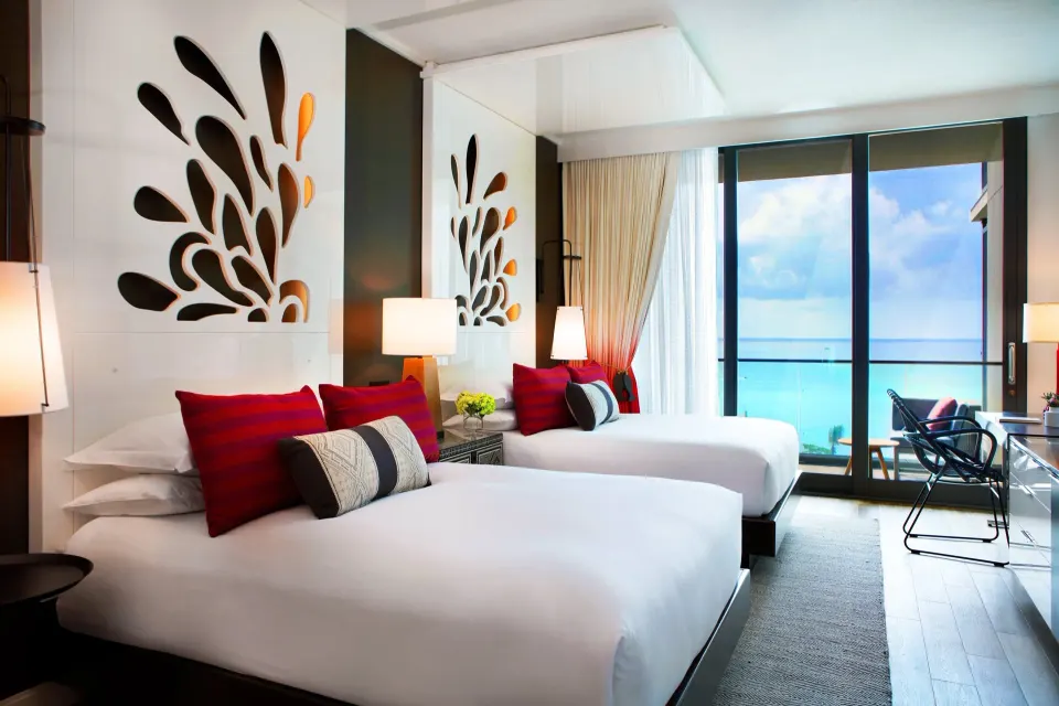 Twin beds and ocean-view balcony in a guest room at Kimpton Seafire Resort + Spa.