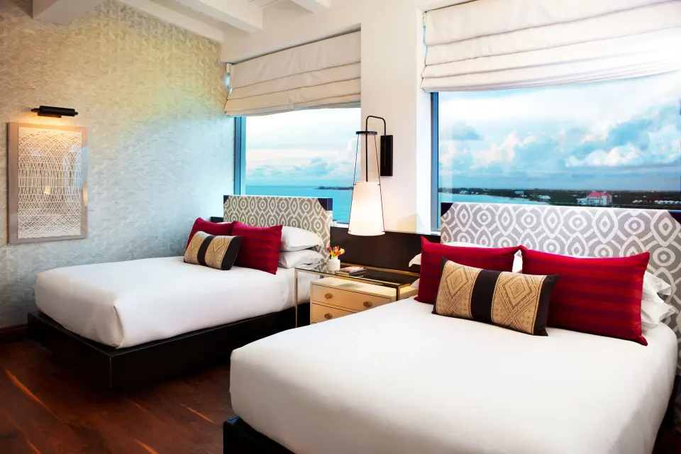 Two double beds with patterned headboards and windows showing ocean at Kimpton Seafire Resort + Spa
