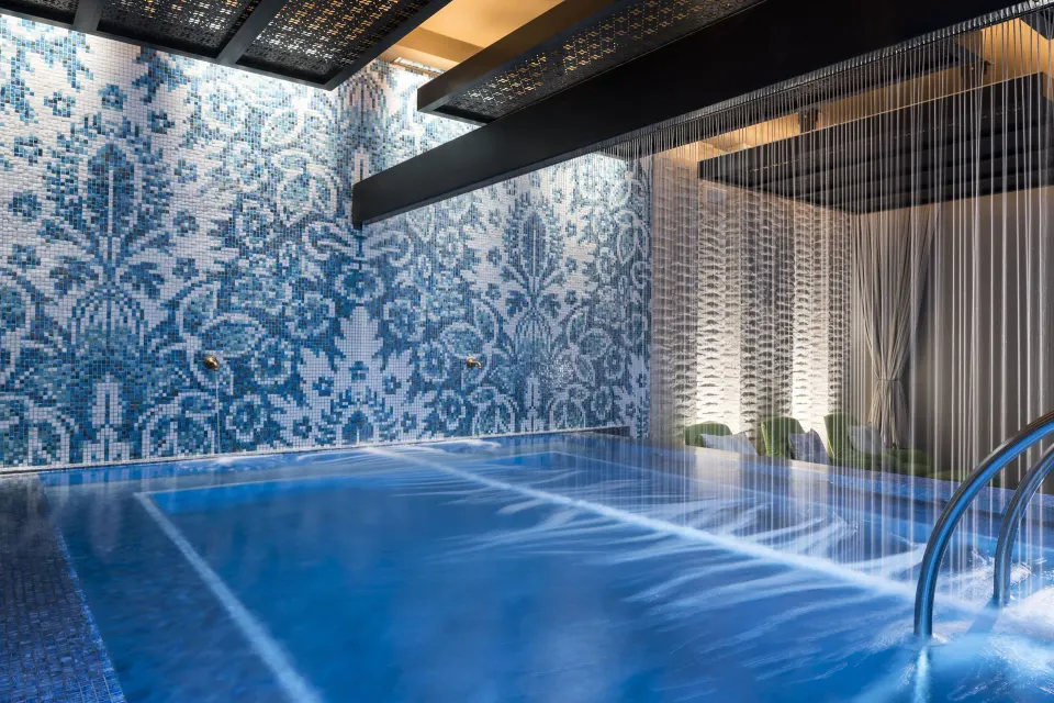 Indoor wellness pool with mosaic wall and water curtain at Kimpton Seafire Resort + Spa