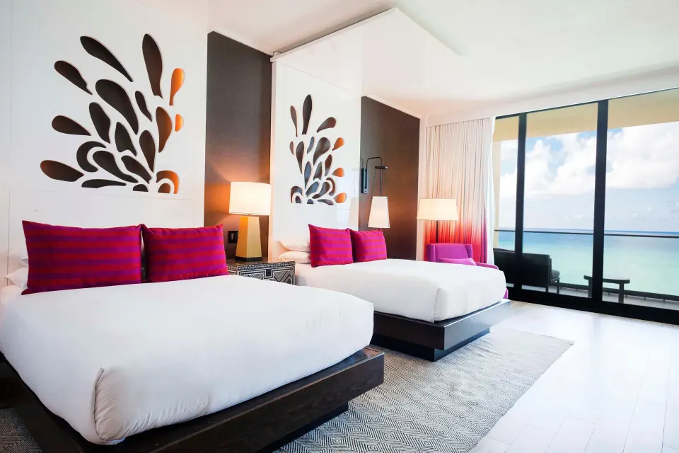 Two beds with bright pink cushions and ocean view at Kimpton Seafire Resort + Spa