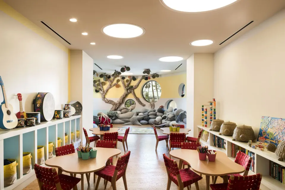Bright children's activity room with small tables and wall play features at Kimpton Seafire Resort + Spa