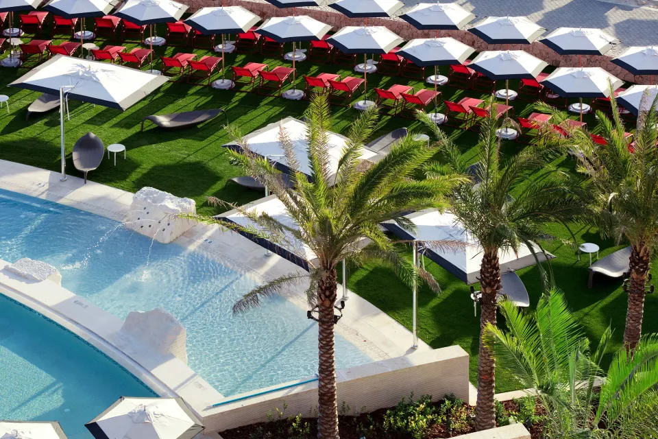 Resort pool deck with palm trees and rows of umbrellas at Kimpton Seafire Resort + Spa