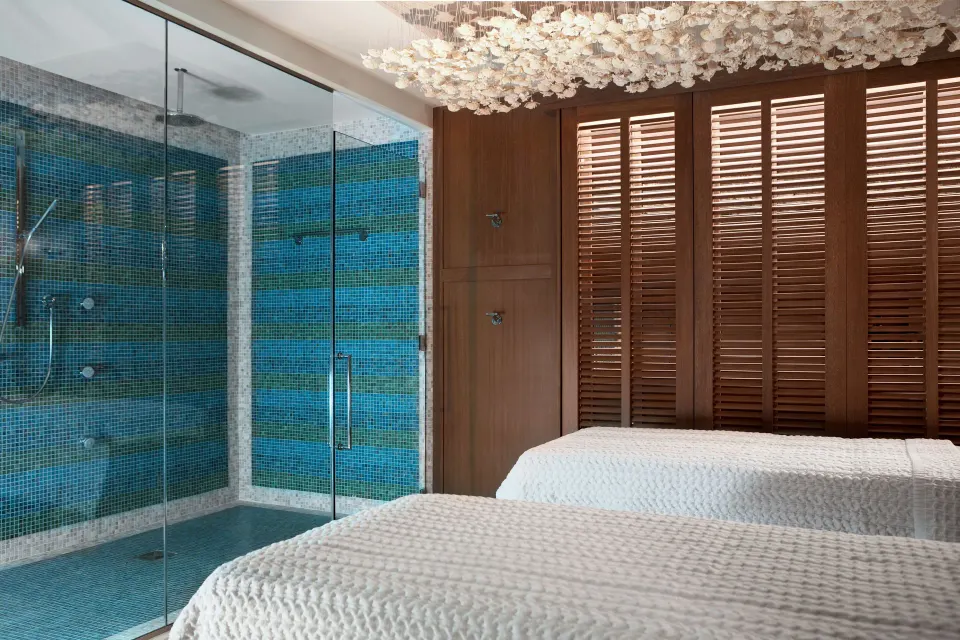 Spa treatment room with twin beds and glass steam shower at Kimpton Seafire Resort + Spa